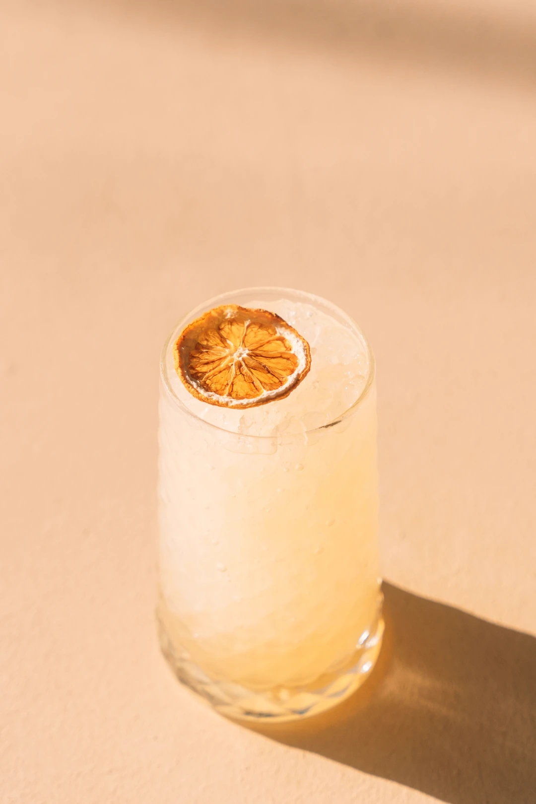 Red cocktail with a dried citrus garnish on a wooden table