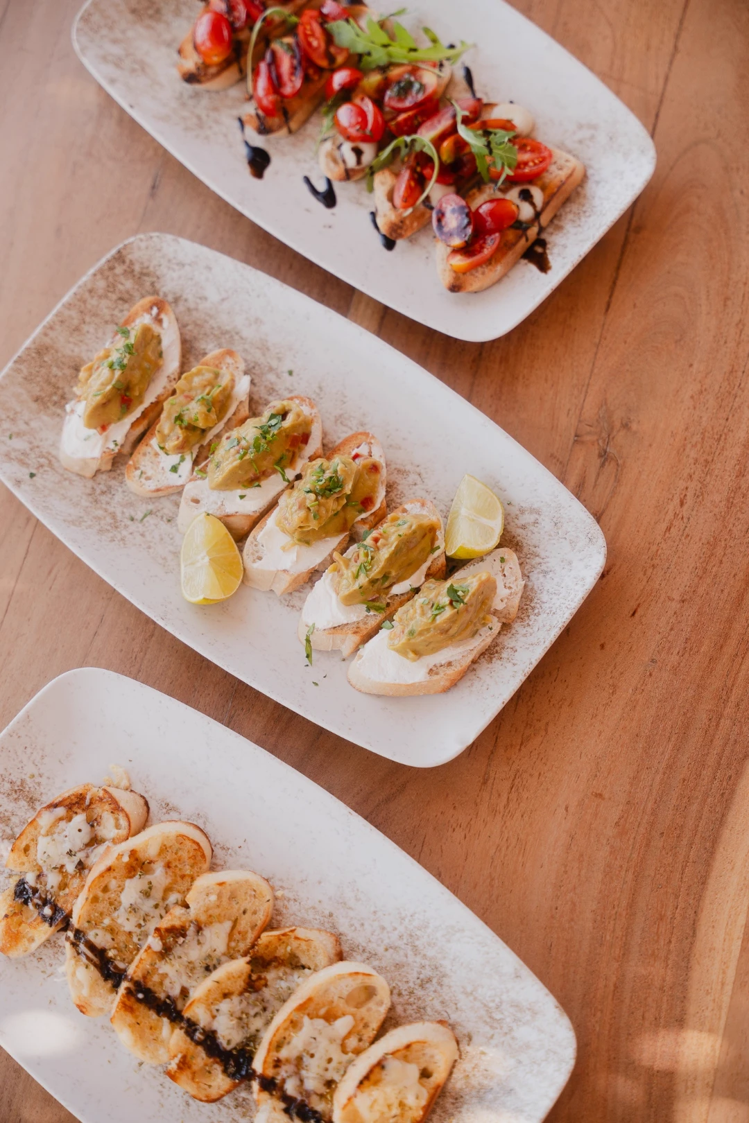 Three plates of bruschetta with tomato, avocado and garlic bread