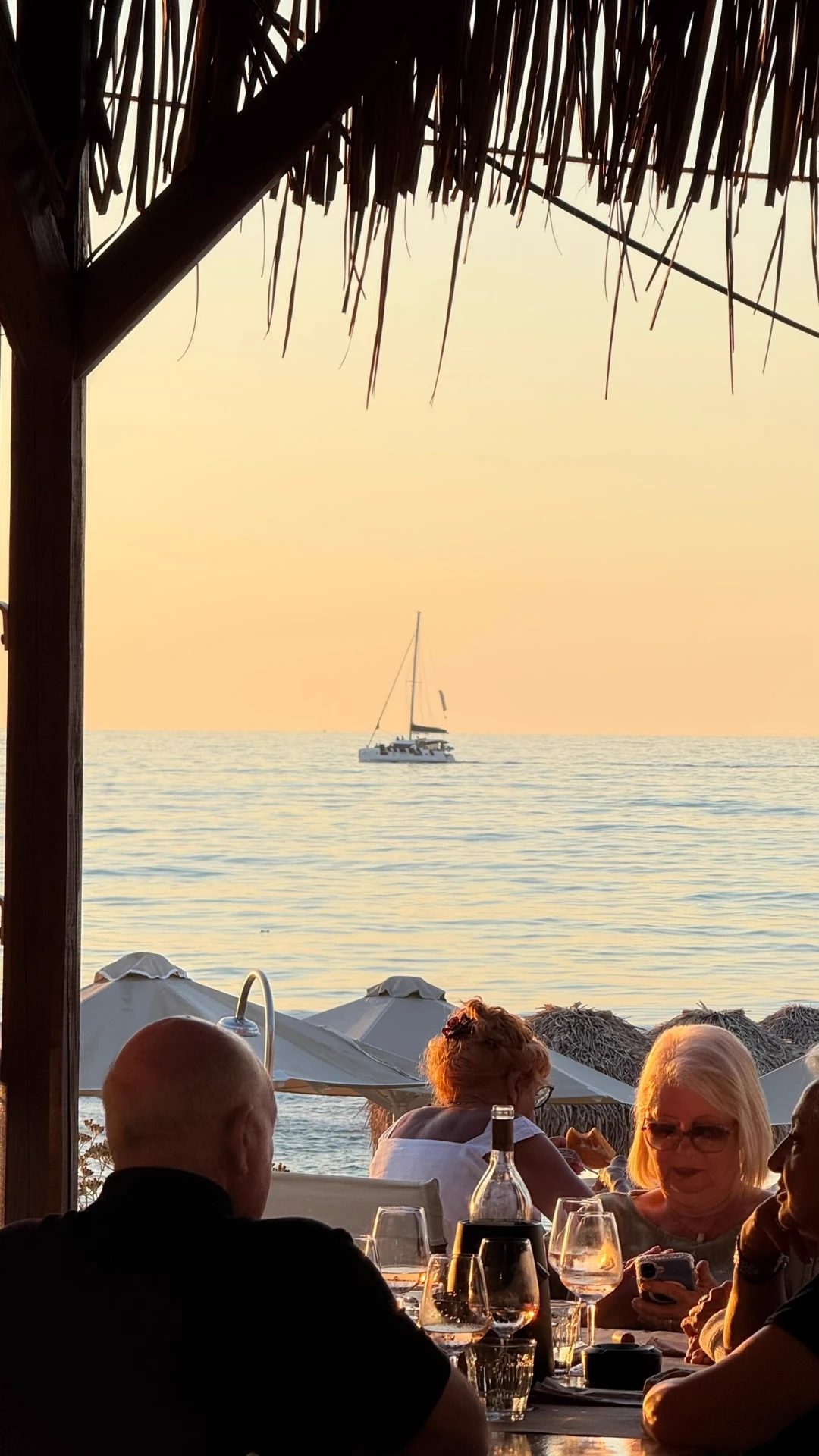Sunset drinks by the water with a sailboat on the horizon